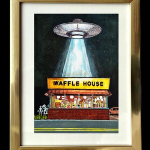 Puede incluir: Una pintura de acuarela enmarcada de un OVNI flotando sobre un restaurante Waffle House por la noche. El OVNI est&aacute; proyectando un rayo de luz hacia abajo sobre el edificio. Dos peque&ntilde;as figuras alien&iacute;genas grises est&aacute;n de pie frente al restaurante. El marco es dorado y mide 31,75x39,37 cm. La impresi&oacute;n con passe-partout mide 27,94x35,56 cm.