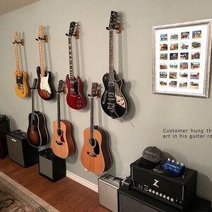 May include: A collection of electric and acoustic guitars mounted on a gray wall. The guitars are various colors, including natural wood, red, and black. A framed artwork with multiple small images hangs on the wall. The text in the image says, "Customer hung this framed art in his guitar room."