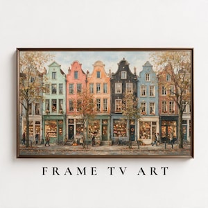 Pode incluir: Uma impressão de arte emoldurada horizontal retratando uma fileira de casas coloridas em estilo europeu com vitrines ao nível da rua. Os edifícios apresentam fachadas em tons pastel e escuros, janelas grandes e árvores de outono. O texto FRAME TV ART está abaixo.
