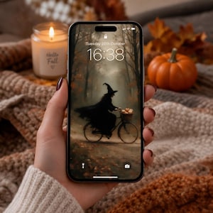 Op de afbeelding: Een smartphone met een vergrendelscherm waarop een digitale illustratie staat van een heks in een zwarte mantel op een fiets in een bos. Het scherm toont de tijd 16:38 en de datum Tuesday 20th October. De telefoon heeft een zwart frame en een notch.
