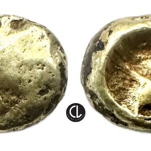 May include: Two gold coins with irregular shapes. One coin has a textured surface, while the other has a concave design. The coins appear to be old and worn, with a matte finish. The image is well-lit, highlighting the details.