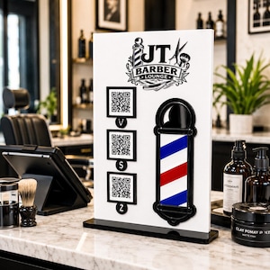 Könnte beinhalten: Ein weißes rechteckiges Schild für JT Barber Lounge mit einem schwarzen Logo, das eine Barber-Stange und eine Schere zeigt, drei schwarz umrahmte QR-Codes mit V-, S- und Z-Symbolen darunter sowie eine große, vertikale, rot-weiß-blaue Barber-Stange.