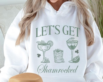 May include: White hoodie with the text "Let's Get Shamrocked" in green lettering. The design includes three green cocktail glasses with a shamrock and lime.