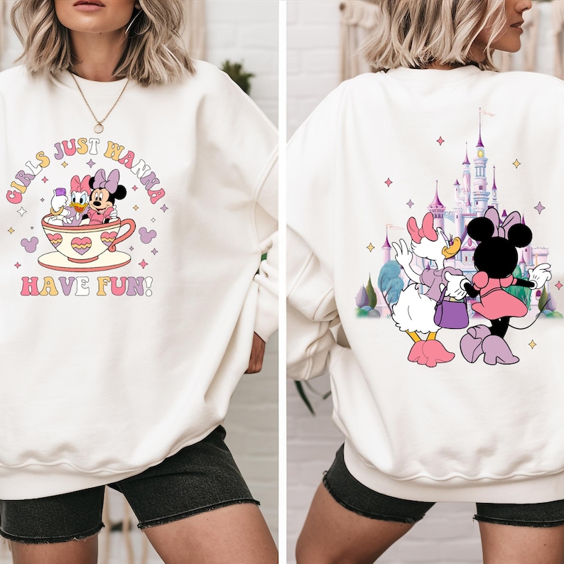 May include: White sweatshirt with a pink and purple graphic of two cartoon characters in a teacup. The text "Girls Just Wanna Have Fun!" is printed on the front of the sweatshirt. The back of the sweatshirt features a pink and purple graphic of a castle and two cartoon characters.