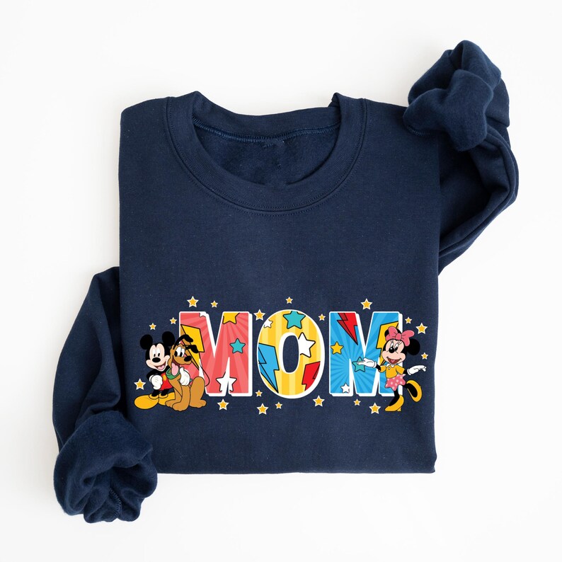 Peut inclure: Sweat-shirt bleu marine avec le mot "MOM" en lettres color&eacute;es et &eacute;toil&eacute;es. Mickey Mouse, Pluto et Minnie Mouse sont repr&eacute;sent&eacute;s sur le sweat-shirt. Col rond.