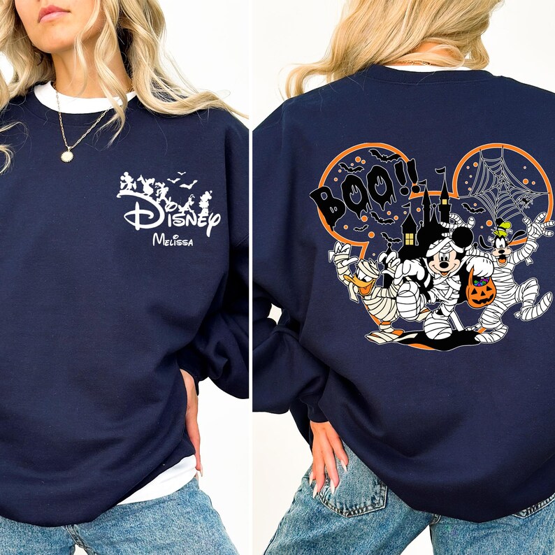 May include: Navy blue sweatshirt with a white collar featuring a Disney Halloween design. The front has a Disney logo and the name "Melissa". The back displays Mickey Mouse, Donald Duck, and Goofy in mummy costumes, with a haunted house and the word "BOO!!".