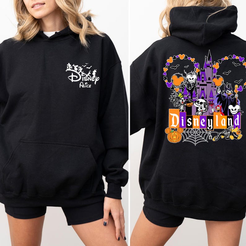 Może przedstawiać: Czarna bluza z kapturem z przednią kieszenią. Prz&oacute;d przedstawia napis "Disney Alice" z sylwetkami postaci. Tył przedstawia projekt Disneylandu z zamkiem, dyniami i postaciami w kolorze fioletowym, pomarańczowym i białym.
