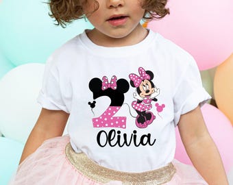 May include: White t-shirt with a pink and black polka dot number 2 and a pink and black polka dot Minnie Mouse graphic. The shirt also has the name "Olivia" printed on it.