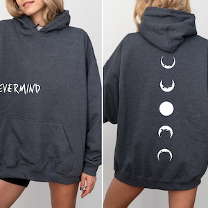 May include: Dark gray hoodie with the word "NEVERMIND" in white on the front. The back of the hoodie features a white moon phase design. The hoodie has a front pocket and a hood.