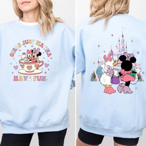 May include: Light blue sweatshirt with a graphic of Mickey Mouse and Minnie Mouse characters in a teacup. The text "Girls Just Wanna Have Fun!" is printed on the front of the sweatshirt.
