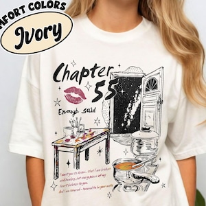 May include: Ivory-colored t-shirt with a graphic design featuring the text "Chapter 55" and "Enough Said." The design includes a drawing of a door, a table, and cooking pots. The shirt also has the words "Comfort Colors" and "Ivory" in a circle.