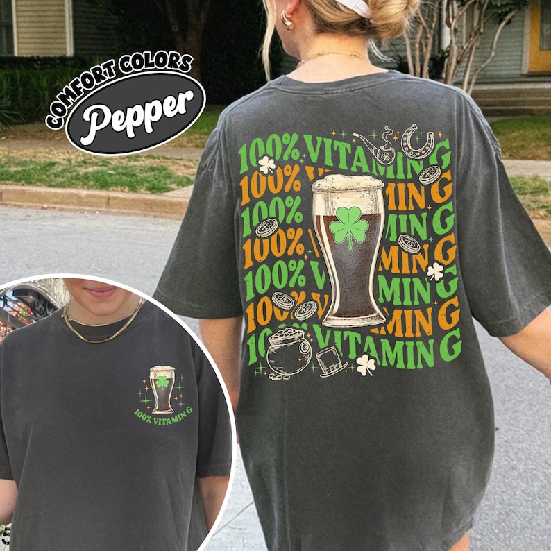 May include: Dark grey t-shirt featuring a beer glass with a shamrock and the text "100% Vitamin G". The shirt also has the text "Comfort Colors" and "Pepper".