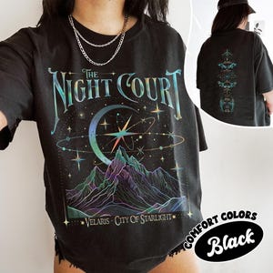 May include: Black t-shirt with a graphic print of a crescent moon, stars, and mountains. The text "The Night Court" is printed above the graphic. The text "Velaris - City of Starlight" is printed below the graphic.