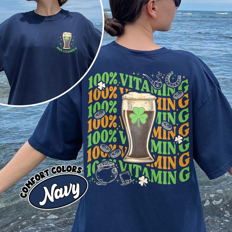 May include: Navy blue t-shirt with a graphic of a beer glass with a shamrock and the text "100% Vitamin G". The shirt also features the text "Comfort Colors Navy".
