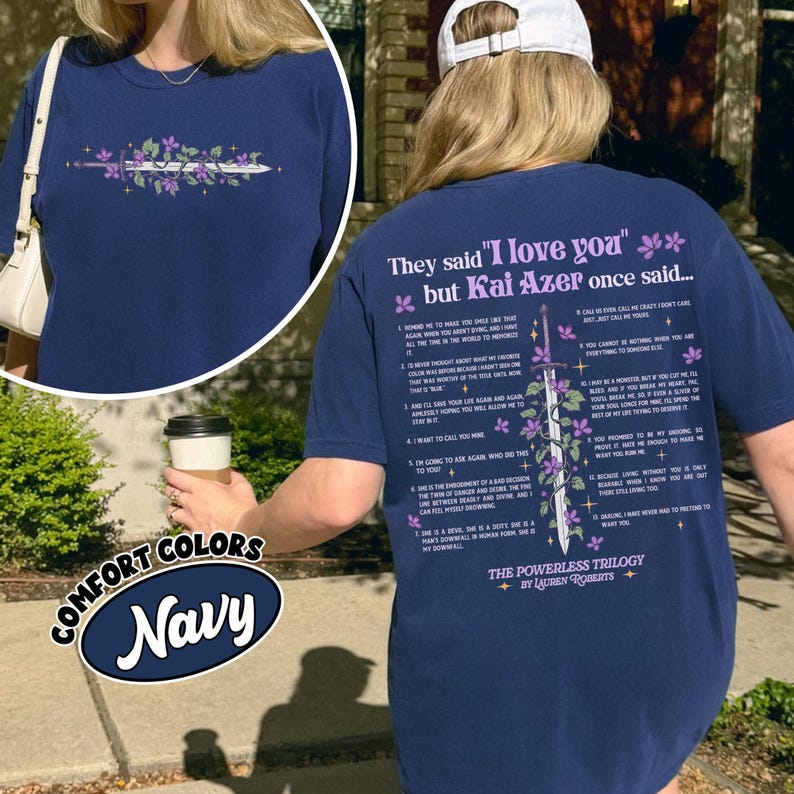 May include: Navy blue t-shirt with a floral and sword design on the front and text on the back. The text on the back reads "They said 'I love you' but Kai Azer once said..." and includes a list of quotes.
