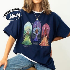 May include: Navy blue t-shirt with a graphic of three women in stained glass windows. The text "Let's go rattle the stars", "To the stars who listen and the dreams that are answered", and "Through love all is possible" is printed on the shirt.