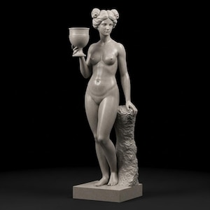 Puede incluir: Estatua desnuda de una mujer sosteniendo un cáliz. La figura está esculpida en piedra gris claro, con rasgos faciales detallados y cabello peinado en moños. Se encuentra sobre una base rectangular, con el brazo izquierdo apoyado en un pilar texturizado. El fondo es negro.