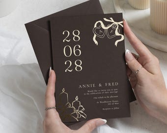 Invitaciones de boda con detalles en lámina dorada, invitación de boda en color marrón chocolate, tipografía elegante, invitación con vela y lazo.