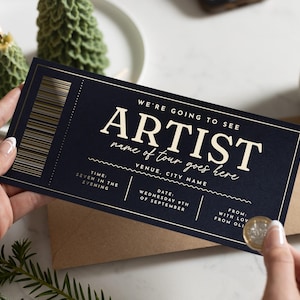 Könnte beinhalten: Eine dunkelblaue Eintrittskarte mit goldenen Akzenten und dem Text "WE'RE GOING TO SEE ARTIST name of tour goes here." Die Karte zeigt Zeit, Datum und Veranstaltungsort. Sie wird über einem braunen Umschlag gehalten.