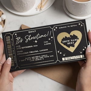 May include: A black and gold theatre ticket with the text "It's Showtime!!" and "Show Name Here". The ticket includes the date, time, and venue, and a scratch-off heart design. The ticket is held by a person.