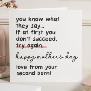 May include: A white greeting card with black text that reads "you know what they say... if at first you don't succeed, try again. happy mother's day love from your second born!" A pink line underlines "try again."