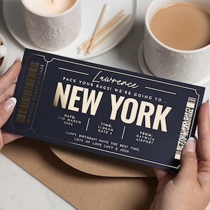 May include: A navy blue boarding pass with gold lettering. The text reads "NEW YORK" in large letters, with details of date, time, and departure airport. The pass is held by two hands. The text includes "Gatwick Airport".