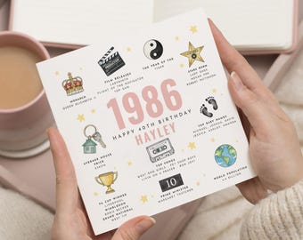May include: A square card with the year 1986 in pink, celebrating a 40th birthday. The card includes illustrations of a film clapper, cassette tape, and a trophy. Text includes the name Hayley, top songs, and world population.