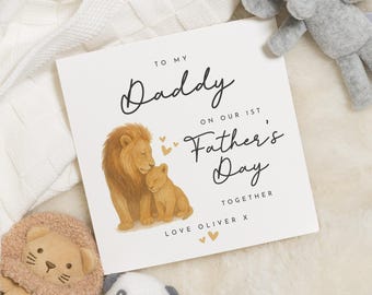 Pode incluir: Um cartão de Dia dos Pais com uma ilustração de leão e filhote. O cartão diz "Para meu papai no nosso 1º Dia dos Pais Juntos" com "Love Oliver X" na parte inferior. O cartão é branco com detalhes em preto e dourado.