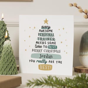 May include: A Christmas card with a tree design, featuring the text "every AWESOME PERSONAL TRAINER needs some time to REST. MERRY CHRISTMAS Jordan YOU really ARE THE BEST!". Two green tree-shaped candles are lit, and a vase with a plant is on the right.