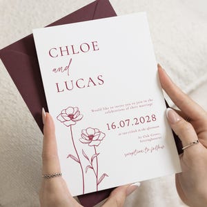May include: A white wedding invitation card with dark red text and floral line art. The text reads CHLOE and LUCAS, 16.07.2028, and details about the marriage at Oak Grove, Sittingbourne. The card is tucked into a dark red envelope.