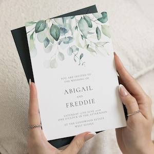 May include: A wedding invitation with a watercolor eucalyptus design. The invitation is white with green and blue leaves and the names Abigail and Freddie. The text reads "You are invited to the wedding of Abigail and Freddie".