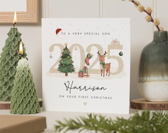 May include: A Christmas card with the text "To a very special son" and "2025". The card features a Christmas tree, reindeer, gifts, and a stocking. The name "Harrison" is written below, with the words "on your first Christmas".