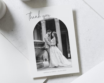 May include: Black and white wedding thank you card with a photo of a couple in front of an archway. The text "Thank you" is written in cursive at the top of the card. The couple's names and wedding date are printed at the bottom of the card: "Emma & Greg | 16.04.2023"