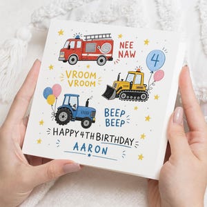 May include: A square greeting card featuring a red fire truck, a yellow bulldozer, and a blue tractor with colorful balloons and yellow stars. The text reads "NEE NAW", "VROOM VROOM", "BEEP BEEP", "HAPPY 4TH BIRTHDAY", and the name "AARON" in blue.
