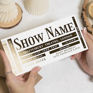 May include: A personalised theatre ticket with the words "SHOW NAME" in a vintage font. The ticket is for Shaftesbury Theatre, London, Friday 21st June 2027, and includes a message. The ticket is held by a person.