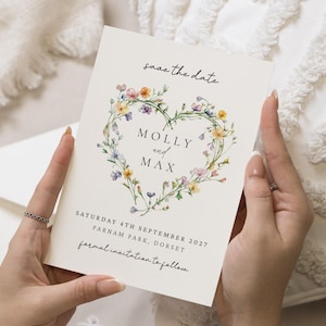 May include: A cream-colored wedding invitation with the text "save the date" at the top. The names "MOLLY and MAX" are centered within a floral heart. The date, location, and "formal invitation to follow" are also printed.