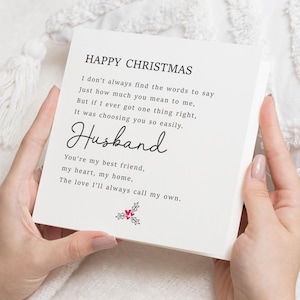 Op de afbeelding: Een witte vierkante kaart met de woorden "Happy Christmas" en een gedicht opgedragen aan een echtgenoot. De kaart heeft een handschriftlettertype en een klein hulst- en bessenontwerp.