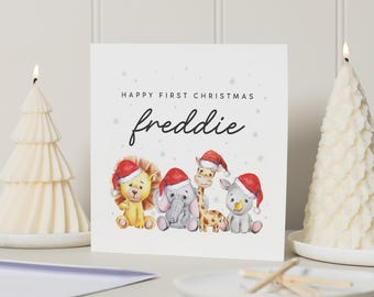 Op de afbeelding: Een witte kaart met de tekst "Prettige eerste Kerst Freddie" en een aquarel-illustratie van vier dieren die kerstmanmutsen dragen. De dieren zijn een leeuw, een olifant, een giraffe en een neushoorn.