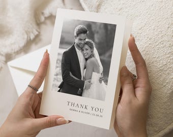 May include: A cream-colored thank you card held by a person. The card features a black and white photograph of a couple embracing. The text "THANK YOU" is printed at the bottom, along with names and a date.
