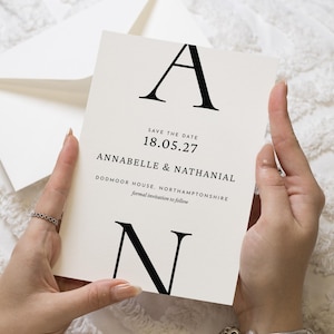 May include: A cream-colored rectangular save the date card featuring large black serif letters A and N at the top and bottom. The text reads SAVE THE DATE 18.05.27 ANNABELLE & NATHANIAL DODMOOR HOUSE, NORTHAMPTONSHIRE formal invitation to follow.