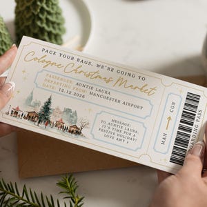 May include: A cream-colored boarding pass with gold and light blue accents, held by a person. The pass reads "Cologne Christmas Market" and features a winter scene illustration. Text includes "Auntie Laura" and "Manchester Airport."