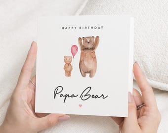 Op de afbeelding: Een witte kaart met de tekst "Happy Birthday Papa Bear" in zwarte cursieve letters. De kaart heeft een aquarel-illustratie van een bruine beer die een roze ballon vasthoudt en een kleinere bruine beer die ernaast staat.