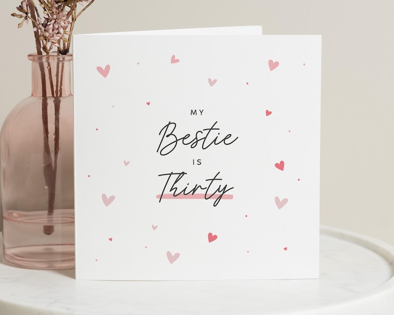Puede incluir: Una tarjeta blanca con corazones rosas esparcidos por los bordes. La tarjeta dice "My bestie is thirty" con una l&iacute;nea rosa debajo de "thirty".