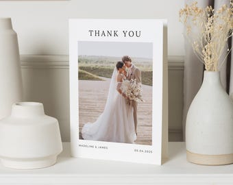 May include: A white thank you card with a photo of a bride and groom in front of a grassy hill. The text "THANK YOU" is at the top of the card, and the names "MADELINE & JAMES" and the date "05.04.2025" are at the bottom.