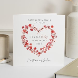 Könnte beinhalten: Weiße Glückwunschkarte mit einem herzförmigen Blumendesign in Rot und Rosa. Der Text lautet "Herzlichen Glückwunsch zum 40-jährigen Rubin-Jubiläum - 2026" und enthält die Namen "Martin und Julia".
