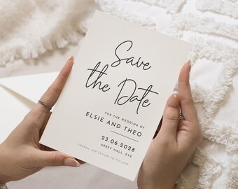 Könnte beinhalten: Eine cremefarbene 'Save the Date'-Karte, gehalten von Händen, mit eleganter schwarzer Schrift. Sie enthält 'Save the Date' sowie die Namen 'Elsie und Theo', das Datum '23.06.2028' und 'Abbey Hall, Eye'. Der Text 'Formelle Einladung folgt' ist ebenfalls vorhanden.