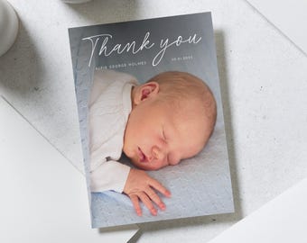May include: Thank you card with a white background and a photo of a baby sleeping on a blue blanket. The text "Thank you" is written in a white cursive font. The baby's name, "Alfie George Holmes", and the date, "30.01.2023", are written below the photo.