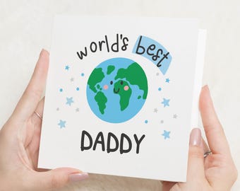May include: A white card with blue and gray stars and the text "world's best daddy" with a blue banner that says "best" and a cartoon earth with a smiling face.