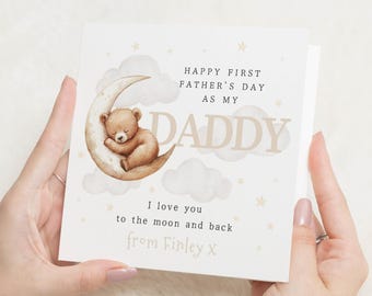 Pode incluir: Um cartão para o Dia dos Pais. O cartão apresenta uma ilustração em aquarela de um ursinho de pelúcia dormindo em uma lua crescente. O texto inclui "Happy First Father's Day as my Daddy" e uma mensagem personalizada.