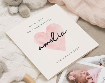 May include: A white card with a pink watercolor heart and the name "amelia" written in black cursive. The text "With love on your baptism 5th March 2022" is printed on the card.